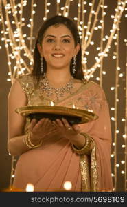 Woman holding a tray of diyas