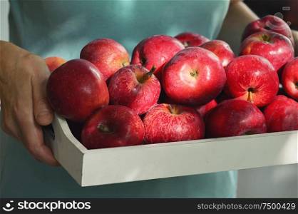Woman holding a wooden bowl full of red apples