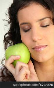 Woman holding apple against face