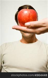 Woman holding apple over man&rsquo;s face