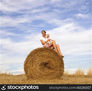 woman holding baby on hay bale