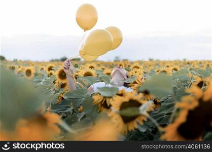 woman holding balloons sunflower field