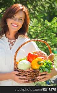 Woman holding basket of vegetables outdoors at her garden