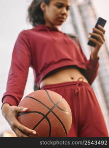 woman holding basketball outdoors checking her phone