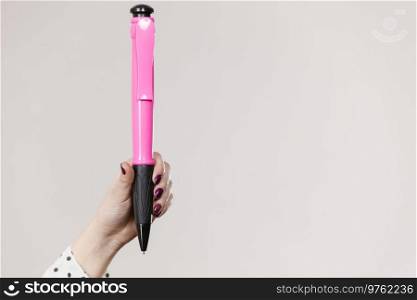 Woman holding big oversized pen. Studio shot on light background with copyspace.. Woman holding big oversized pen