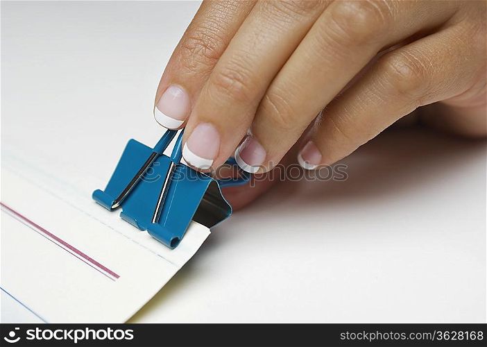 Woman holding binder clip, close-up of hand