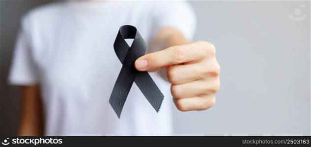 Woman holding black Ribbon for Melanoma and skin cancer, Vaccine injury awareness month, grief and rest in peace. Healthcare and Racist concept