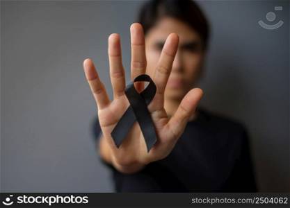 Woman holding black Ribbon for Melanoma and skin cancer, Vaccine injury awareness month, grief and rest in peace. Healthcare and Racist concept