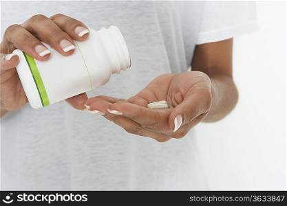 Woman holding bottle of pills, mid section