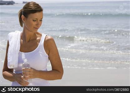 Woman holding bottle of water at the beach