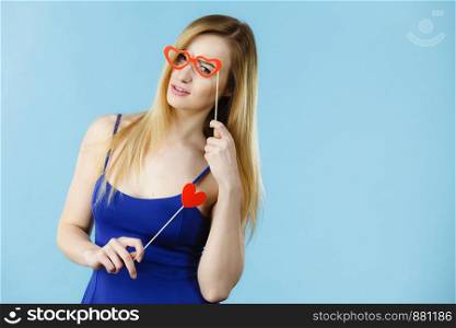 Woman holding carnival accessoies on stick having fun. Studio shot on blue background.. Woman holding carnival accessoies on stick