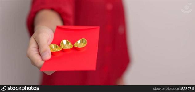 Woman holding Chinese red envelope with gold bullion, money gift for happy Lunar New Year holiday. Chinese sentence means happiness, healthy, Lucky and Wealthy