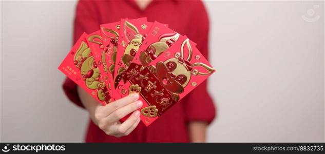 Woman holding Chinese red envelope with golden rabbit and blessing word, money gift for happy Lunar New Year holiday. Chinese sentence means happiness, healthy, Lucky and Wealthy