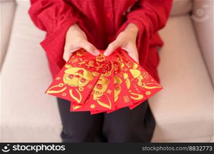 woman holding Chinese red envelope with golden rabbit and blessing word, money gift for happy Lunar New Year holiday. Chinese sentence means happiness, healthy, Lucky and Wealthy