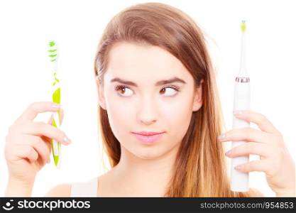 Woman holding, choosing between electric and traditional toothbrush, have to make decision what is best for teeth.. Woman holding electric and traditional toothbrush