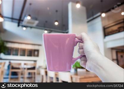 Woman holding coffee cup with abstract blur coffee shop, stock photo