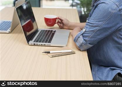 woman holding coffee cup with laptop computer, notebook and pen for use as working concept