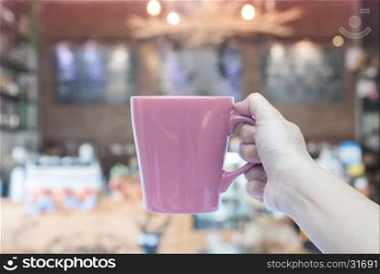 Woman holding coffee mug with blurred cafe background, stock photo