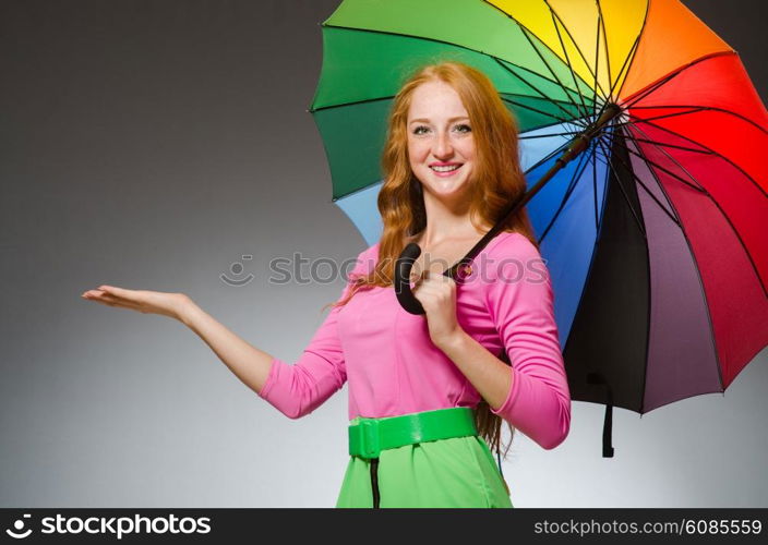 Woman holding colourful umbrella in studio