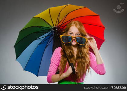 Woman holding colourful umbrella in studio