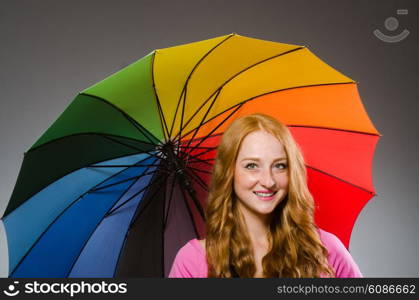 Woman holding colourful umbrella in studio