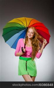 Woman holding colourful umbrella in studio