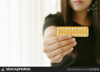 Woman holding contraception pills at home, closeup. Gynecology concept