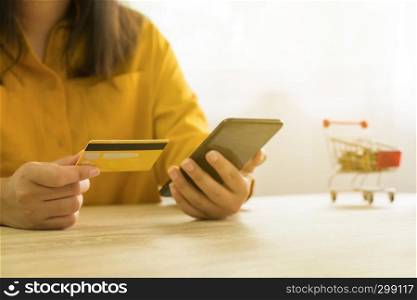 Woman holding credit card and using smartphone for shopping online