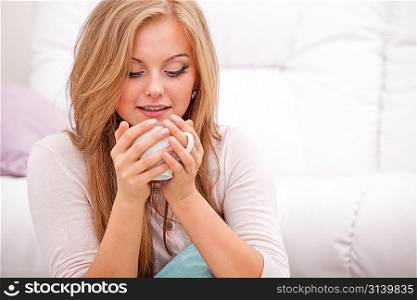 Woman holding cup of coffee and enjoying the smell of its aroma