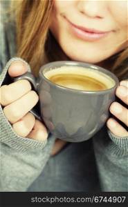 woman holding cup of coffee and smiles