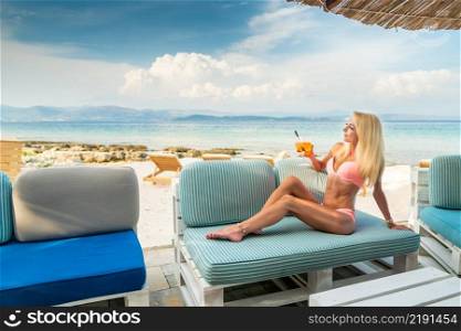 Woman holding Delicious classic iced aperol spritz cocktail with ice cubes on a hot tropical beach in summer sunshine close-up. Woman holding Delicious classic iced aperol spritz cocktail with ice cubes on a hot tropical beach in summer sunshine