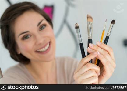 woman holding different make up brushes