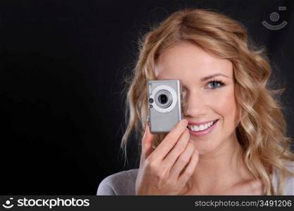 Woman holding digital camera on dark background