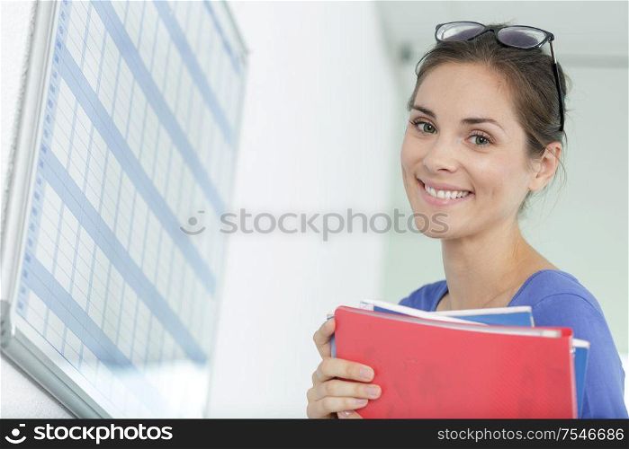 woman holding files stood by a calendar wall planner