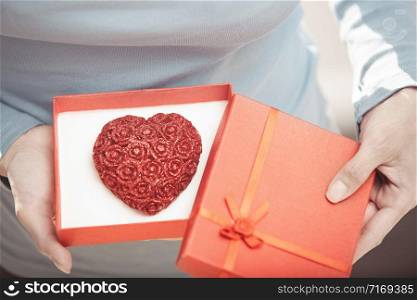 Woman holding gift box with cake in form of heart