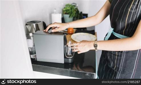 woman holding glass mug coffee machine kitchen
