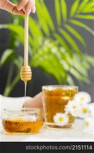 woman holding glass with tea honey dipper