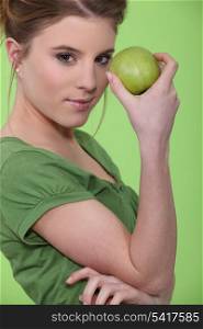 Woman holding green apple against face