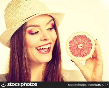 Woman holding half of grapefruit citrus fruit in hand. Woman attractive long hair girl colorful eyes makeup holding half of grapefruit citrus fruit in hand. Healthy diet food. Summer holidays fun concept