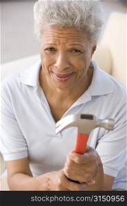 Woman holding hammer looking unsure