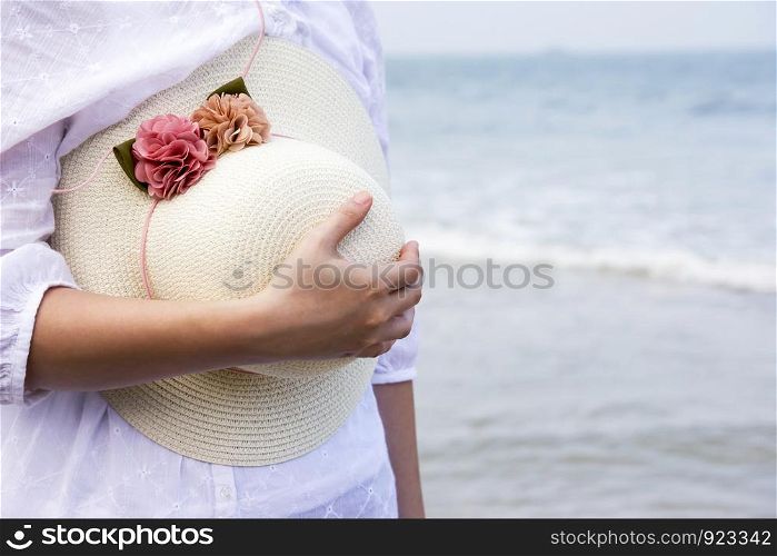Woman holding hat on the beach
