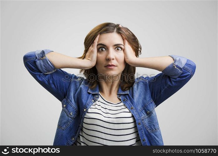 Woman holding head in hands with a astonished expression