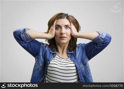 Woman holding head in hands with a astonished expression