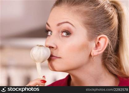 Woman holding healthy herb, two fresh natural garlic smelling it. Healthy eating and dieting concept.. Woman holding and smelling garlic