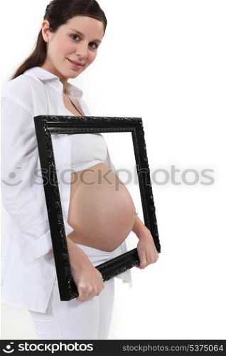 Woman holding her pregnant tummy in a frame