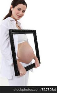 Woman holding her pregnant tummy in a frame