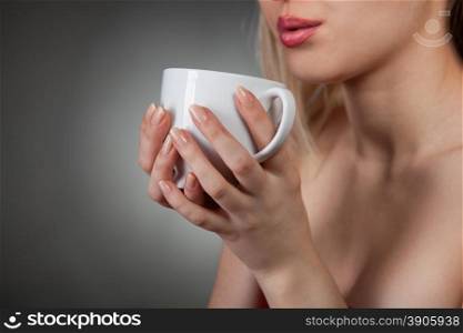 woman holding hot cup and blowing on it