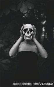 woman holding human skull forest