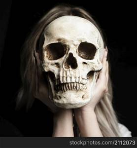 woman holding human skull with black background