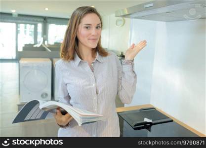 Woman holding instruction book and presenting new cooker